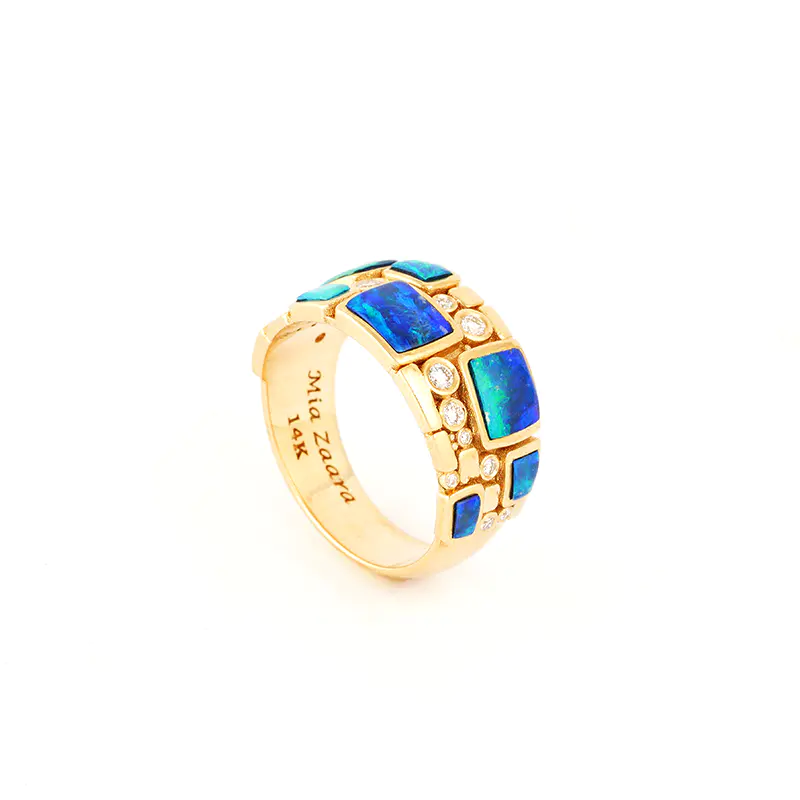 Three-quarter rear view of a gold ring by Navajo jewelry designer Mia Zaara Hamdouni, showing geometric blue opal inlay and diamond accents, with the maker’s mark visible inside the polished band.