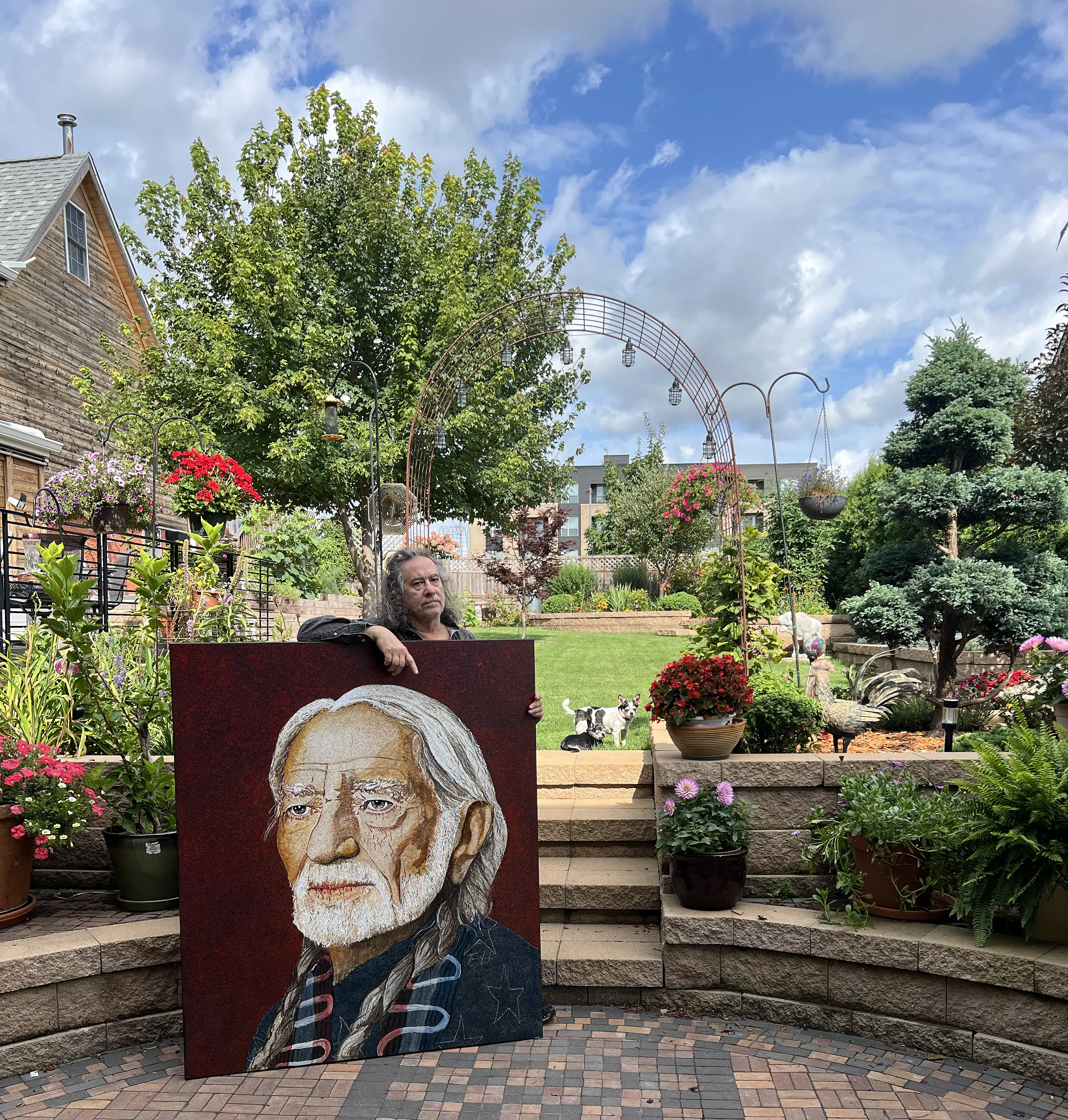Tomas Lasansky in his studio garden with a splatter painting of Willie Nelson