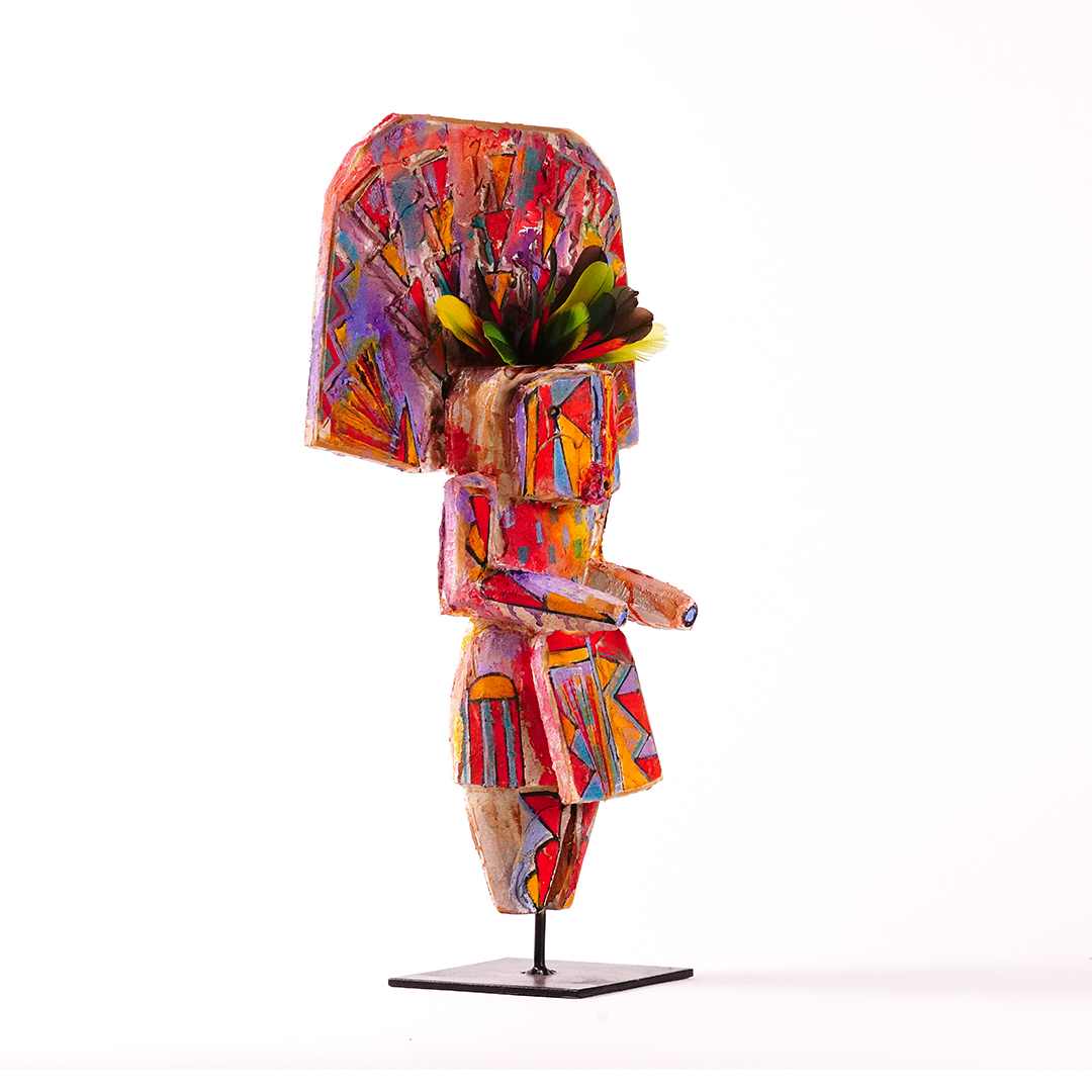 Sheldon Harvey Yei wood sculpture, angled side view, hand-painted with colorful geometric patterns and feather accents on a black metal base.