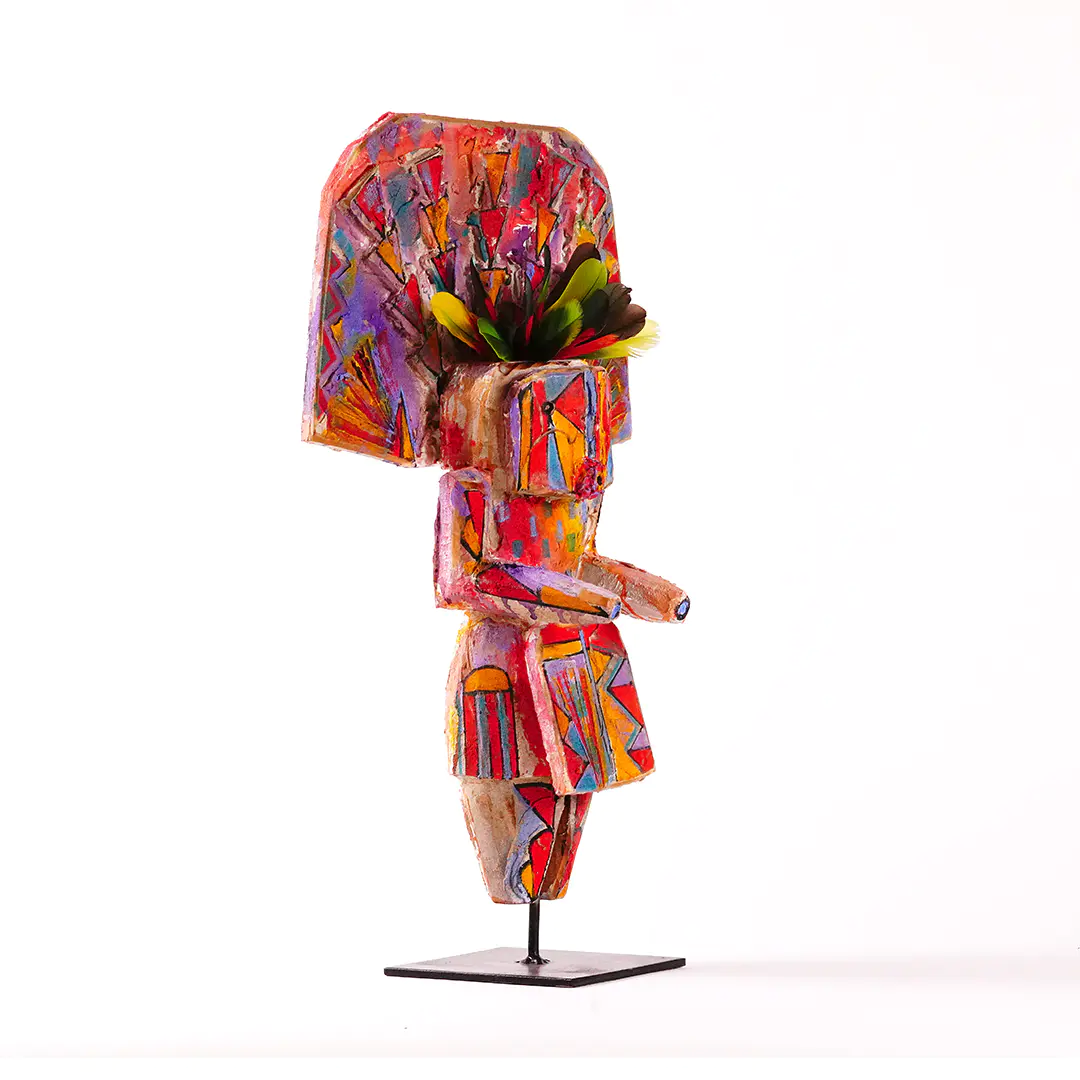 Sheldon Harvey Yei wood sculpture, angled side view, hand-painted with colorful geometric patterns and feather accents on a black metal base.
