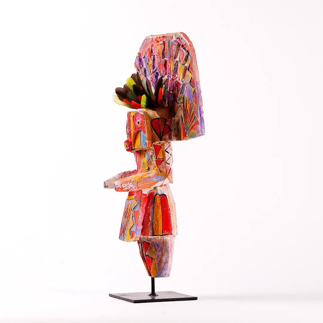 Side view of a stylized Navajo Yei wood sculpture by Sheldon Harvey, hand-painted in vivid colors with feather accents and mounted on a black metal base.