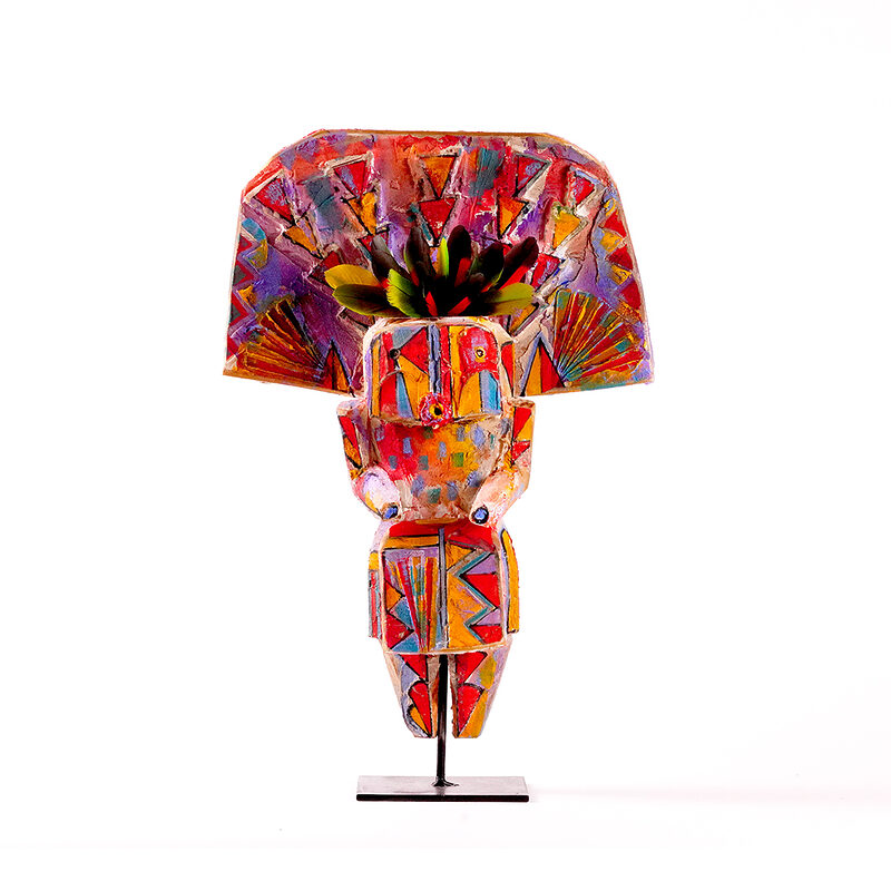 olorful carved wood sculpture titled Yei by Sheldon Harvey, showing a stylized human figure with a wide fan-shaped headdress, geometric painted patterns, and a black floral or feather-like form at the top, mounted on a metal stand against a white background.