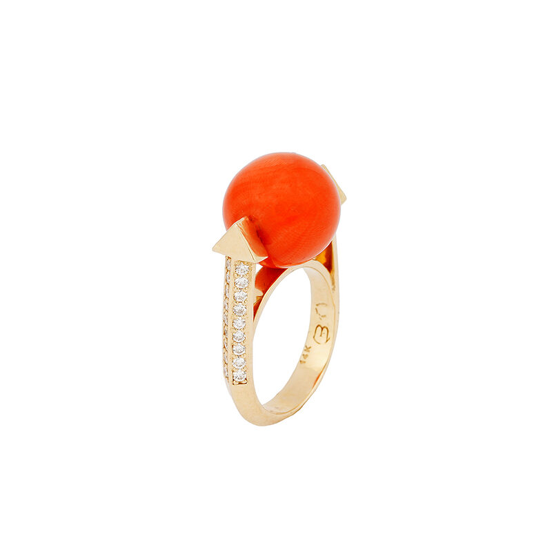 Bo Monongye 14k gold ring with a red-orange coral ball held between two gold arrow points and a diamond-set shank